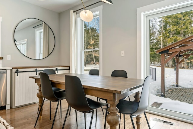 dining area with light wood-style flooring and visible vents