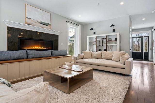 living room with a tiled fireplace, recessed lighting, a healthy amount of sunlight, and wood-type flooring