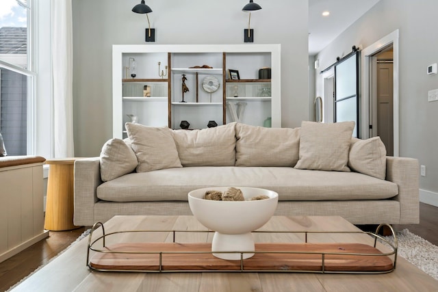 living area with a barn door, recessed lighting, and wood finished floors