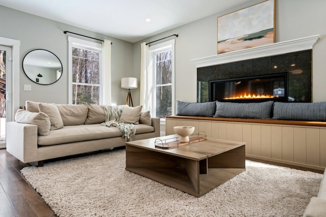 living room with a tile fireplace and wood finished floors