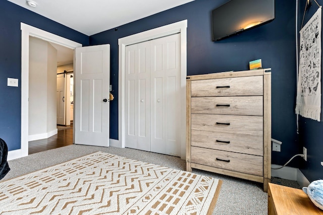 bedroom with a barn door, baseboards, carpet, and a closet