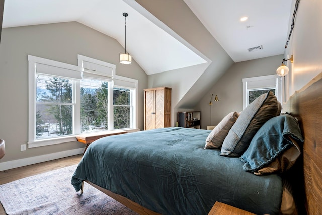 bedroom with vaulted ceiling, wood finished floors, visible vents, and baseboards