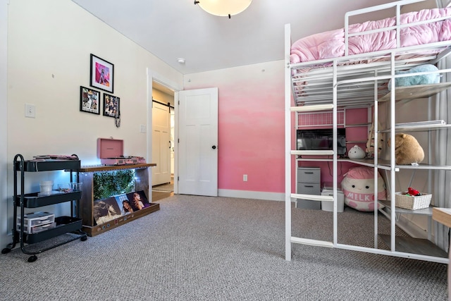 carpeted bedroom with a barn door and baseboards