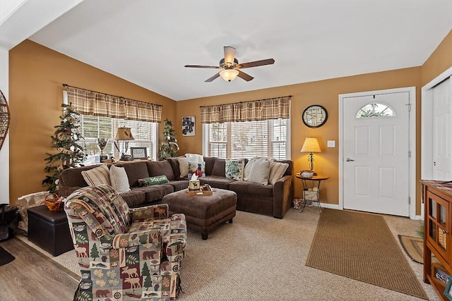 carpeted living room with baseboards, vaulted ceiling, and a ceiling fan