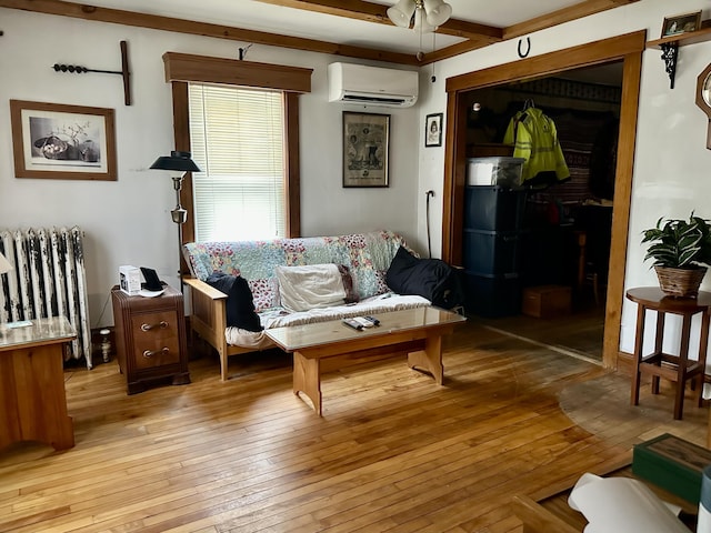 living area featuring ceiling fan, a wall mounted air conditioner, light wood-style flooring, and radiator