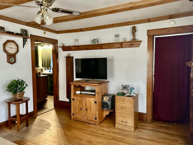 living area with light wood-style floors, ceiling fan, baseboards, and beam ceiling