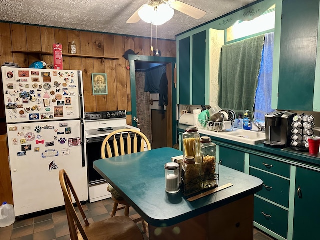 kitchen featuring a textured ceiling, a sink, freestanding refrigerator, electric range oven, and green cabinetry