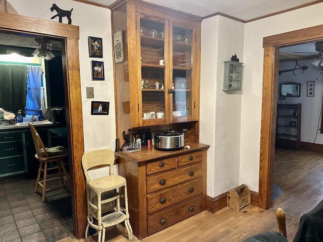 bar with dark wood-style floors, ceiling fan, baseboards, and crown molding