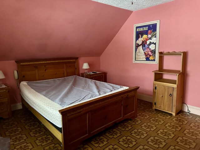 bedroom with lofted ceiling and baseboards