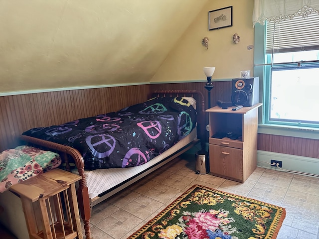 bedroom with a wainscoted wall, vaulted ceiling, and wooden walls