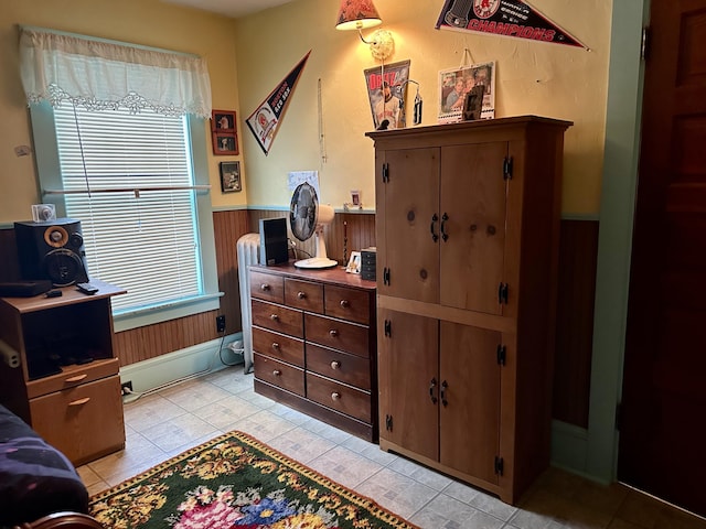 bedroom with a wainscoted wall, wood walls, and radiator heating unit