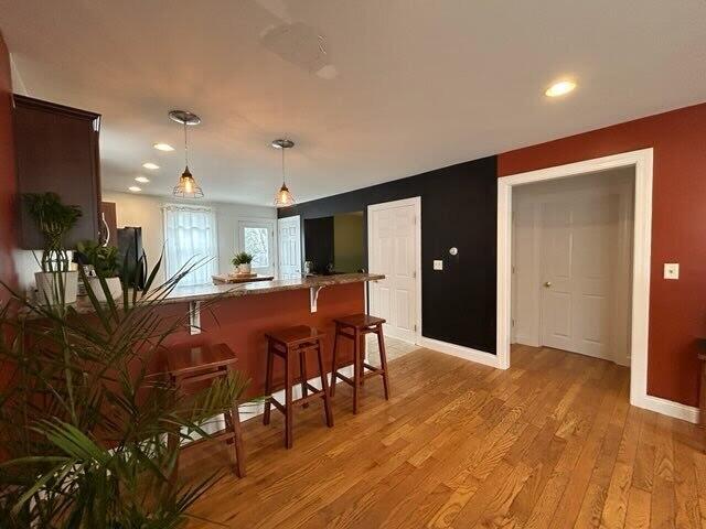 kitchen featuring light wood finished floors, baseboards, a breakfast bar, freestanding refrigerator, and pendant lighting