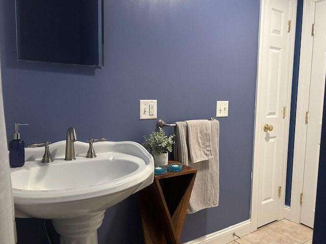 bathroom featuring baseboards, a sink, and tile patterned floors