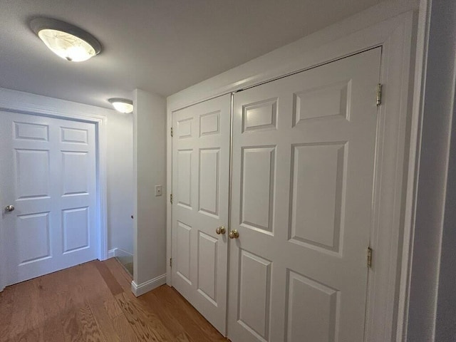 corridor featuring wood finished floors and baseboards