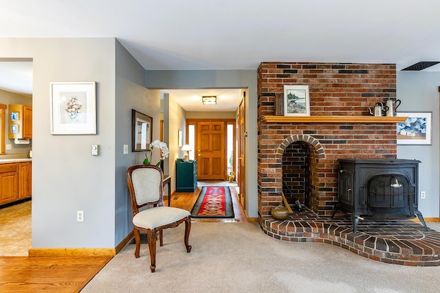 interior space featuring a wood stove, baseboards, and light colored carpet