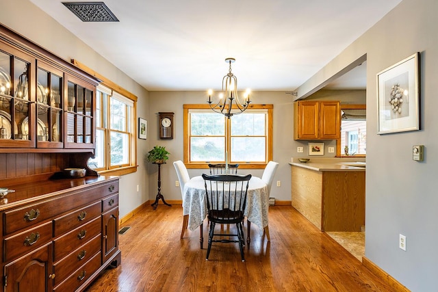 dining area with baseboards, a notable chandelier, visible vents, and wood finished floors