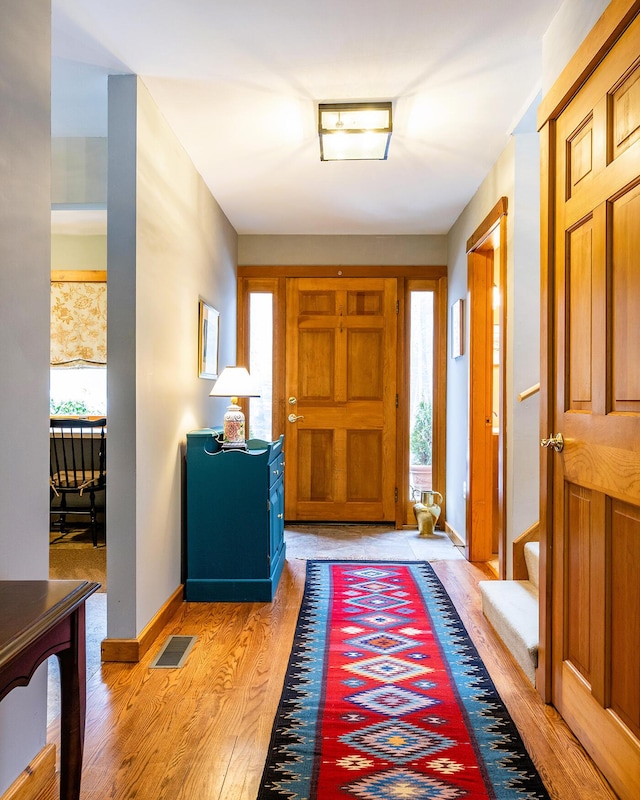 foyer entrance featuring light wood-style flooring, visible vents, and baseboards