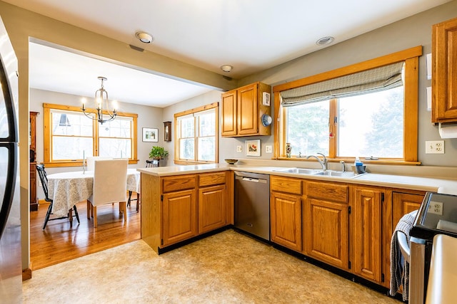 kitchen featuring a peninsula, appliances with stainless steel finishes, brown cabinetry, and a sink