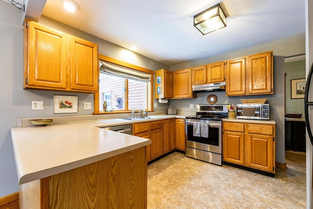 kitchen with under cabinet range hood, a peninsula, a sink, light countertops, and appliances with stainless steel finishes