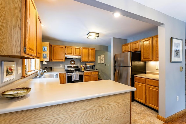 kitchen with a peninsula, stainless steel appliances, light countertops, under cabinet range hood, and a sink