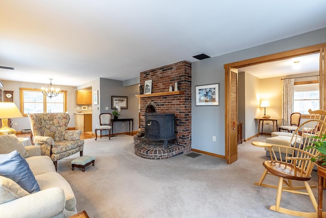 living room featuring visible vents, baseboards, light colored carpet, a wood stove, and a chandelier