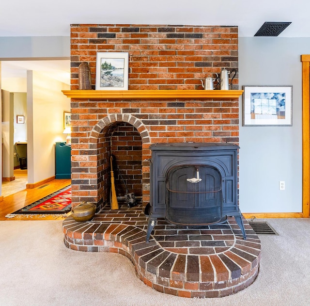 room details featuring a wood stove, carpet, baseboards, and visible vents