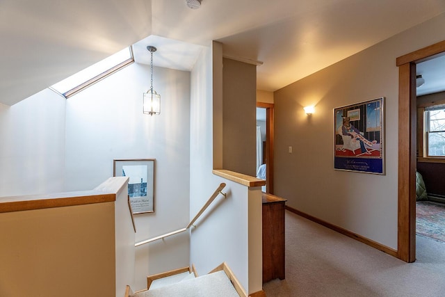 hallway with carpet floors, baseboards, and an upstairs landing