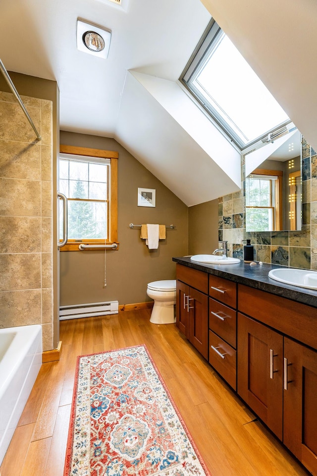 bathroom featuring a healthy amount of sunlight, a sink, baseboard heating, and wood finished floors