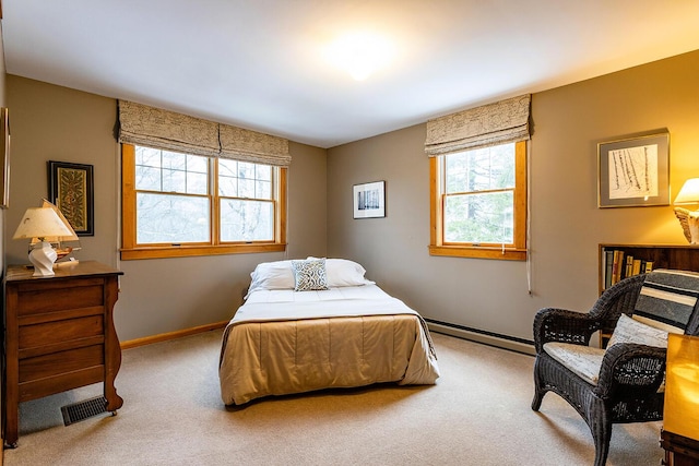 carpeted bedroom featuring a baseboard radiator, multiple windows, baseboards, and visible vents