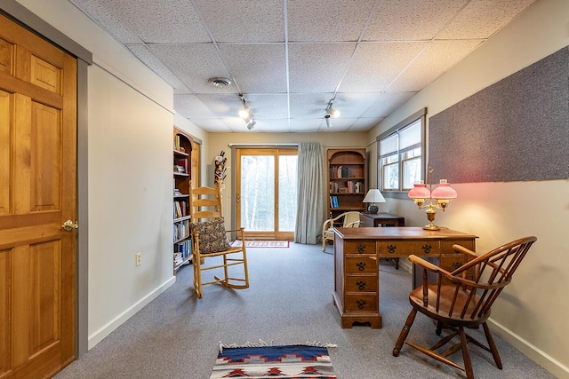 carpeted office featuring a paneled ceiling, baseboards, visible vents, and track lighting