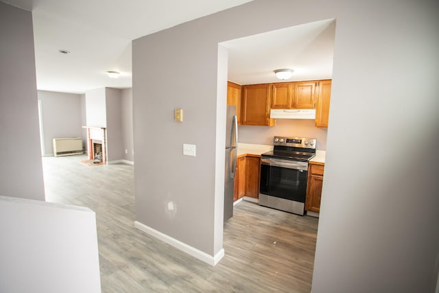 kitchen with under cabinet range hood, appliances with stainless steel finishes, light countertops, and light wood-style floors