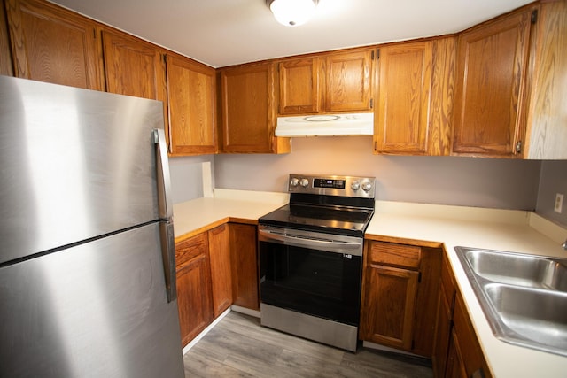 kitchen featuring a sink, light countertops, under cabinet range hood, and stainless steel appliances