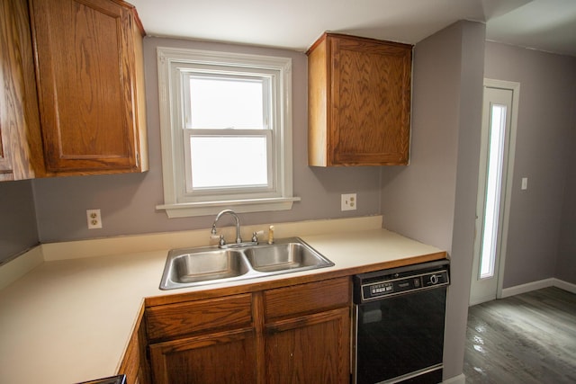 kitchen featuring wood finished floors, a sink, light countertops, black dishwasher, and brown cabinets