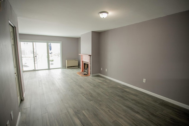 unfurnished living room with a fireplace, dark wood-type flooring, and baseboards