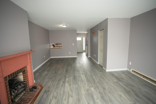 unfurnished living room with a fireplace, baseboards, and wood finished floors