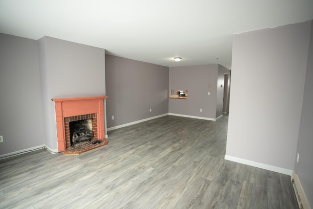 unfurnished living room featuring baseboards, wood finished floors, and a fireplace