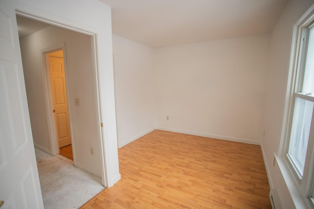 spare room featuring light wood-style floors, baseboards, and a baseboard radiator