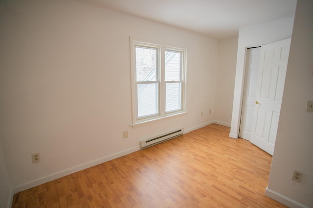 unfurnished bedroom with a baseboard radiator, baseboards, and light wood-style floors