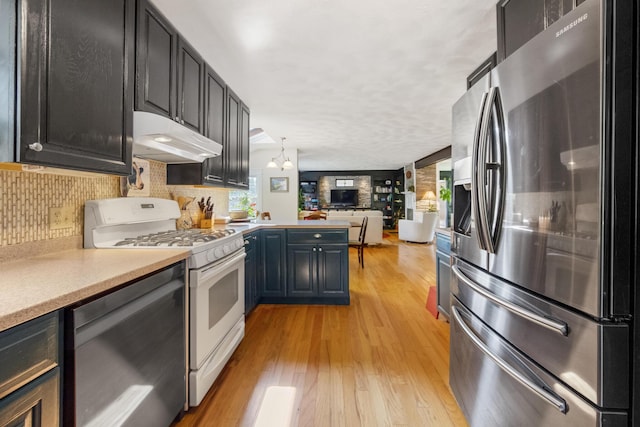 kitchen featuring light wood-style floors, appliances with stainless steel finishes, open floor plan, light countertops, and under cabinet range hood