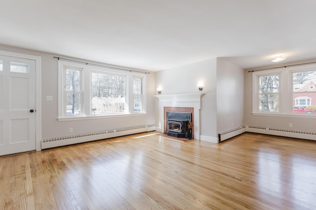 unfurnished living room featuring wood finished floors, a healthy amount of sunlight, and baseboard heating