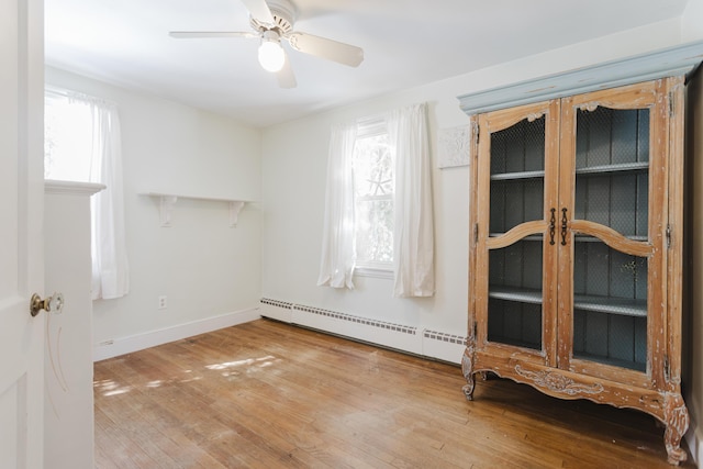 spare room with a wealth of natural light, a baseboard radiator, and wood-type flooring