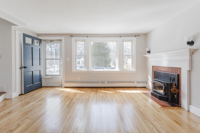 unfurnished living room with a baseboard heating unit, wood finished floors, and baseboards