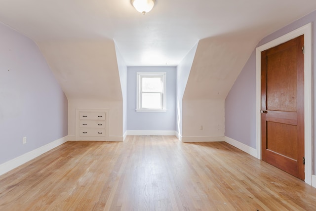 bonus room featuring light wood-style flooring, baseboards, and vaulted ceiling