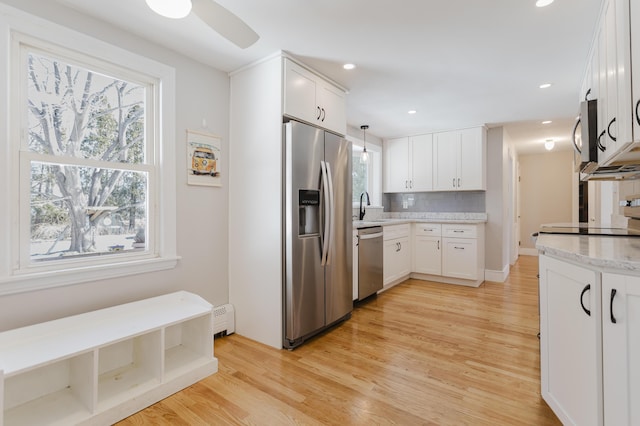 kitchen featuring a sink, stainless steel appliances, baseboard heating, and a healthy amount of sunlight