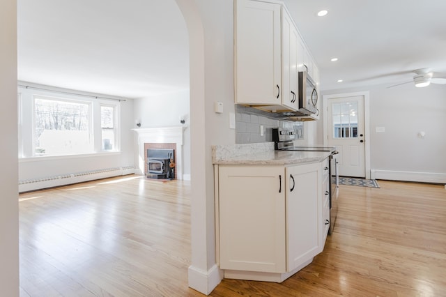 kitchen featuring light wood-style flooring, a baseboard heating unit, white cabinetry, arched walkways, and appliances with stainless steel finishes