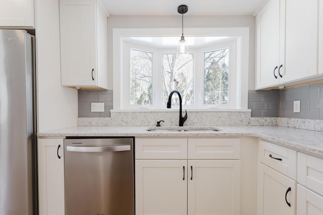 kitchen featuring a sink, light stone counters, backsplash, white cabinetry, and appliances with stainless steel finishes