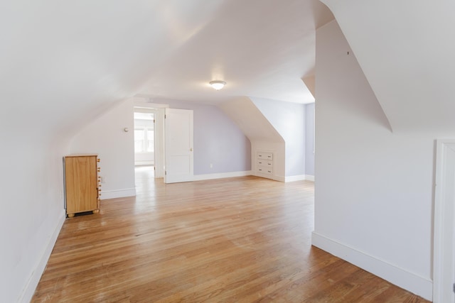 additional living space with lofted ceiling, light wood-style floors, and baseboards