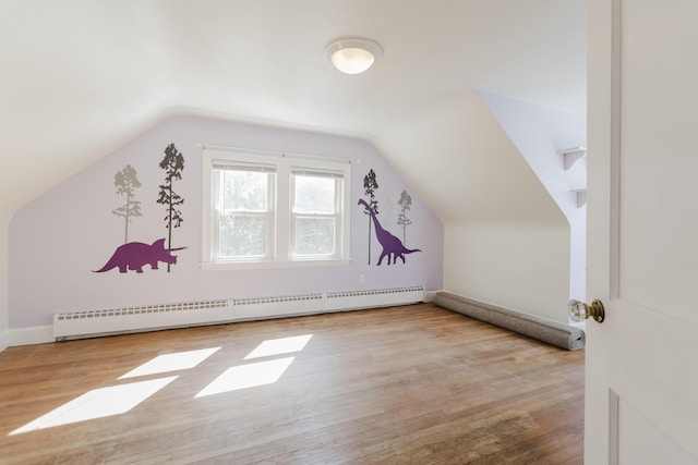 additional living space featuring a baseboard heating unit, wood finished floors, and vaulted ceiling