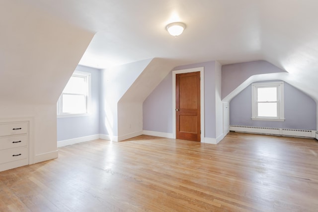 bonus room featuring a baseboard radiator, baseboards, lofted ceiling, and light wood-style flooring