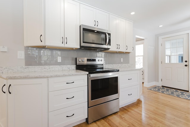 kitchen featuring decorative backsplash, light wood-style floors, appliances with stainless steel finishes, and white cabinetry